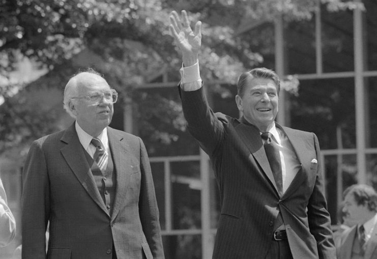 US President Ronald Reagan waving while CIA Director William Casey walks beside him