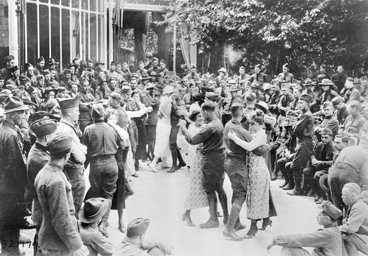 Members of the 353rd Infantry Regiment, 89th Infantry Division dancing with women in the middle of a large crowd