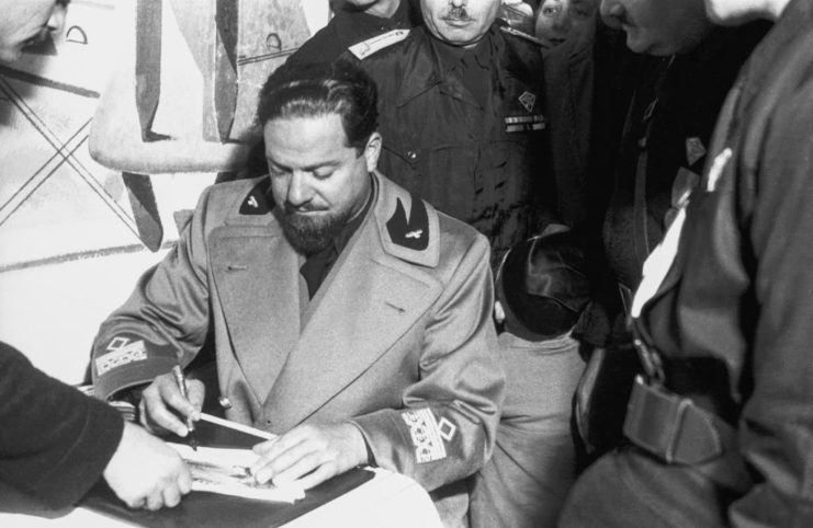 Italo Balbo signing a document while other government officials watch