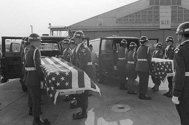 US Army military police loading two American flag-draped caskets into hearses