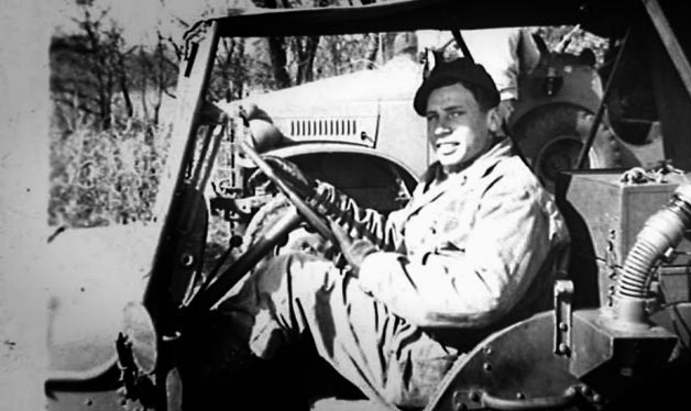 Mel Brooks sitting in the driver's seat of a military vehicle
