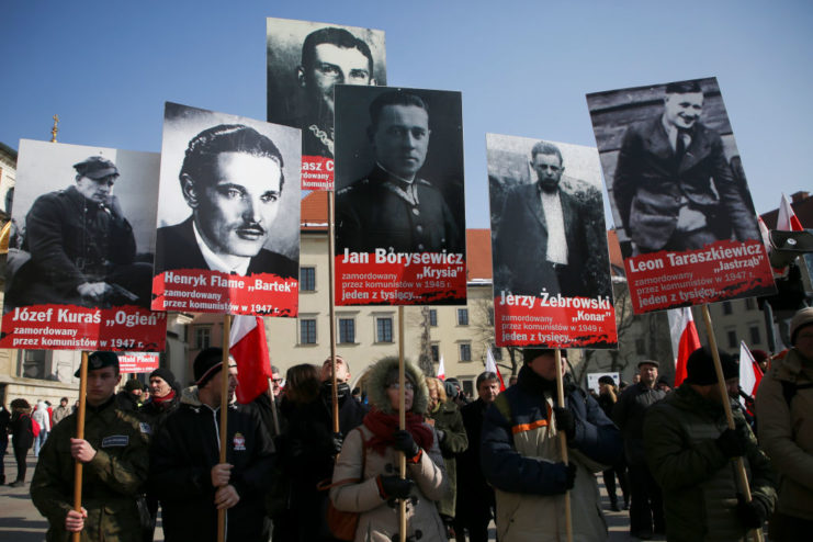Polish citizens holding up signs with pictures of some of the "Cursed Soldiers"