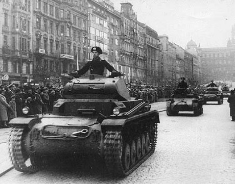 Row of German tanks driving down a street lined with people