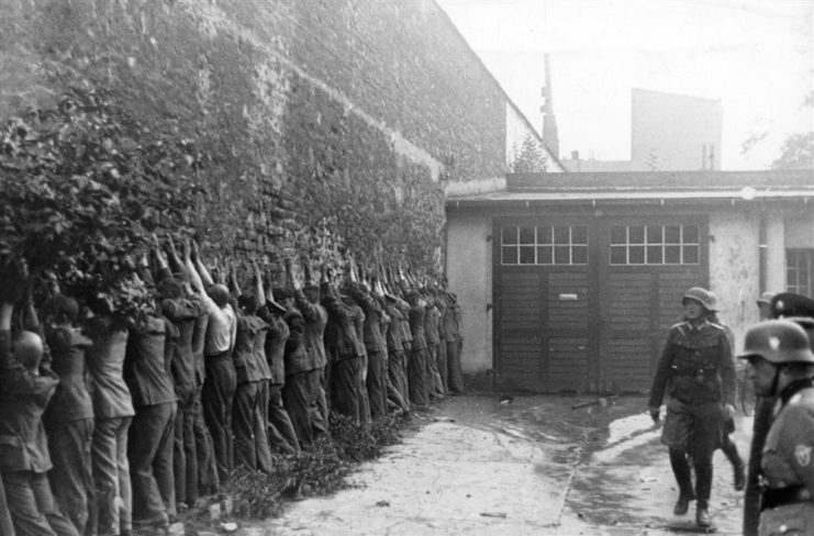 Prisoners from the Polish Post Office lined up against a wall, in front of German soldiers