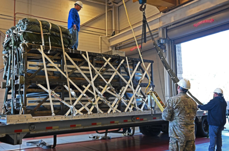 Airmen and riggers standing around a Rapid Dragon Palletized Weapon System