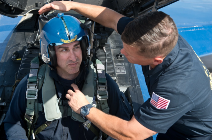 US Navy aviator strapping Rob Riggle into the cockpit of a McDonnell Douglas F/A-18 Hornet