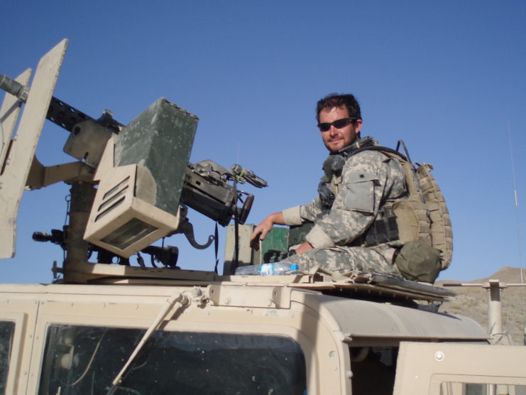 Staff Sgt. Ronald J Shurer II sitting atop an armored vehicle