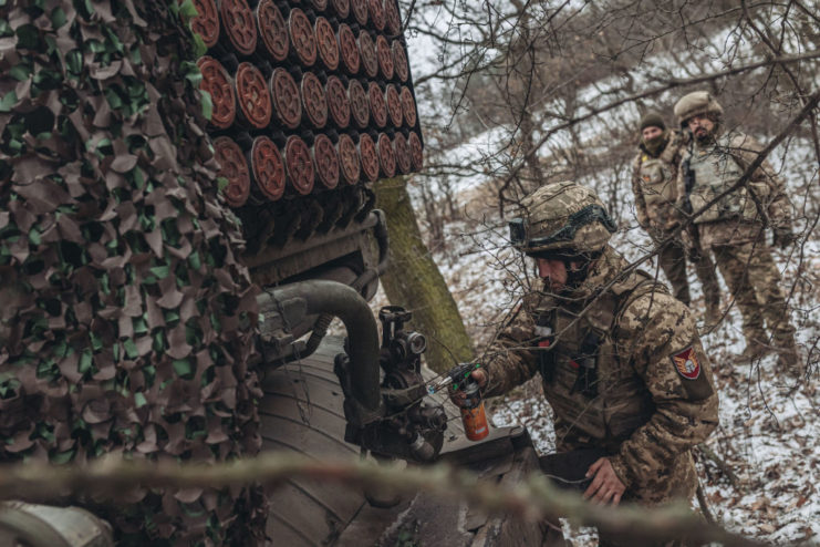 Ukrainian soldier standing next to a BM-21 "Grad" rocket launcher