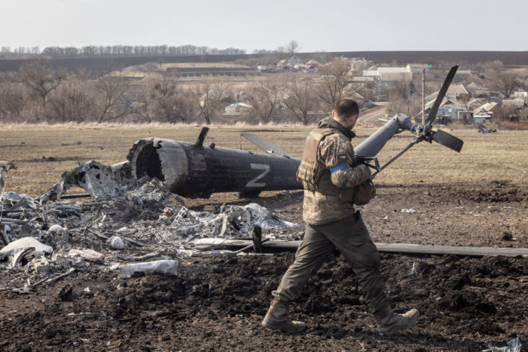 Ukrainian soldier walking past a downed Russian helicopter