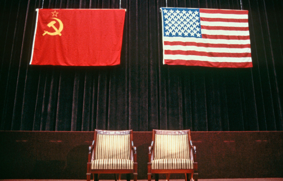 Soviet and American flags hanging over two empty chairs