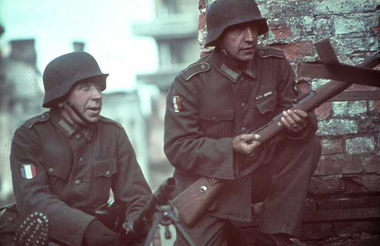 Two Légion des volontaires français contre le bolchevisme soldiers taking cover behind a brick building