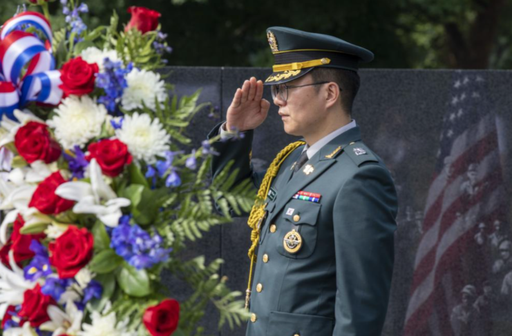 Soldier standing at attention in front of a large wreath