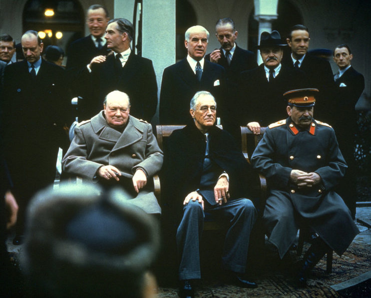 Government officials standing around Winston Churchill, Franklin D. Roosevelt and Joseph Stalin