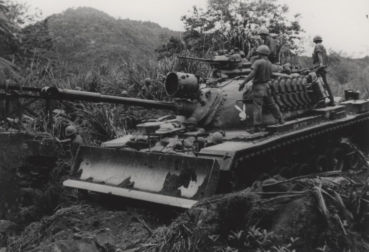 Members of the 1st Tank Battalion riding atop a bulldozer tank