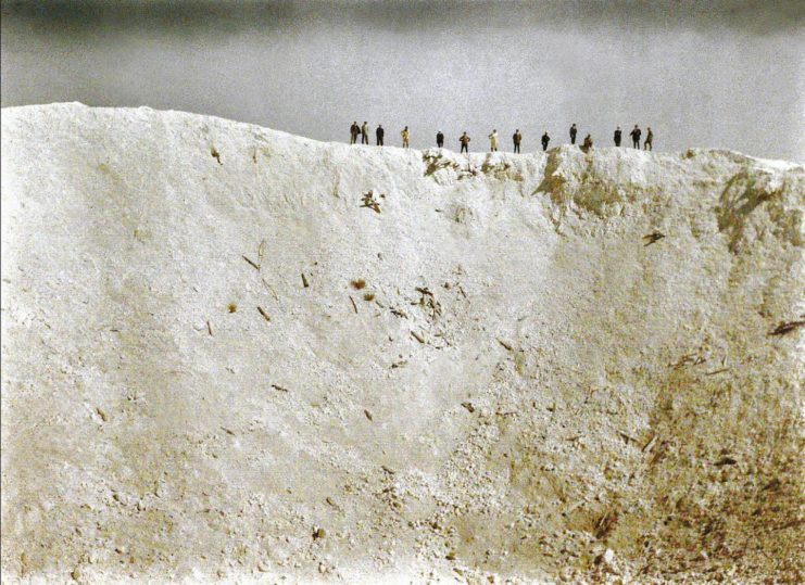 Men standing along the ridge of a 45-meter-deep crater