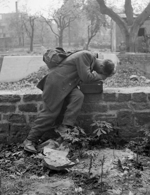 German soldier sitting on a brick wall, crying