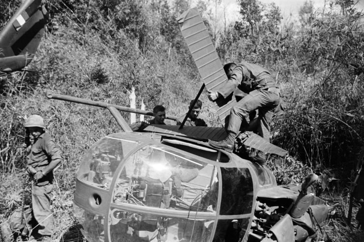 Four US Army soldiers working on a grounded Hughes OH-6 Cayuse