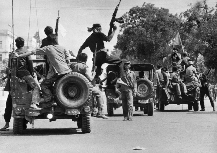 Khmer Rouge guerrilla fighters riding on the backs of Jeeps