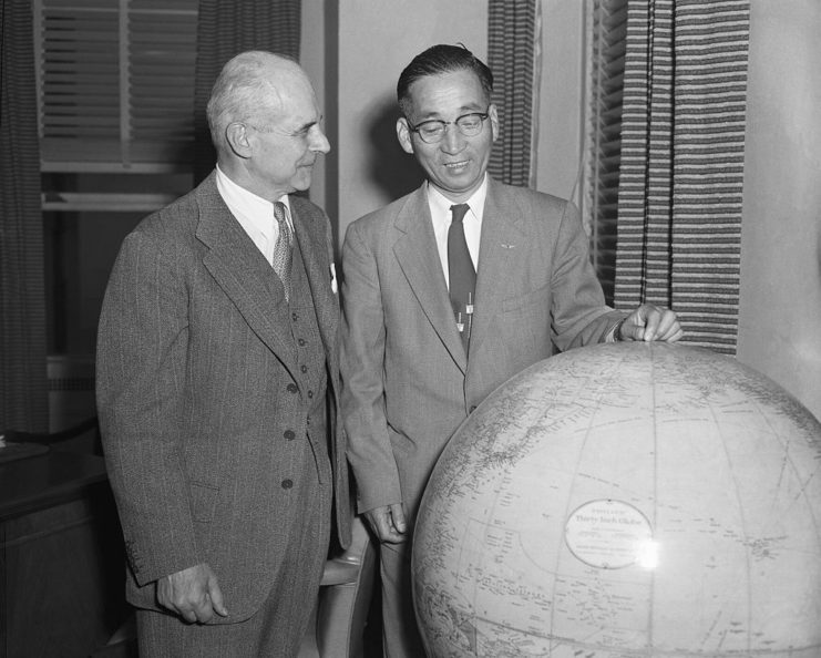 Jimmy Doolittle and Mitsuo Fuchida standing next to a large globe