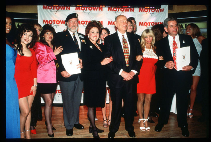 Ed Koch standing with US military veterans and Playboy Playmates