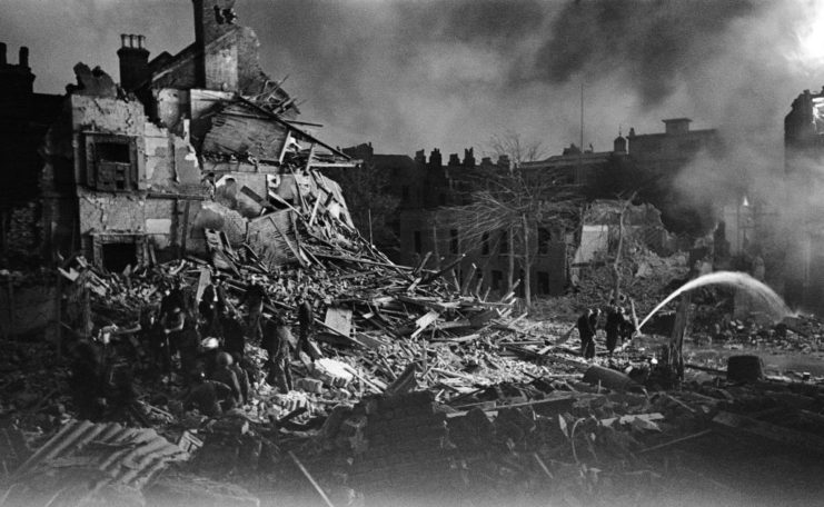 Firefighters putting out flames near a demolished house