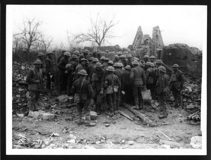 British "Tommies" standing around a destroyed cottage