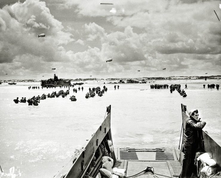 Soldiers wading through water, away from landing craft