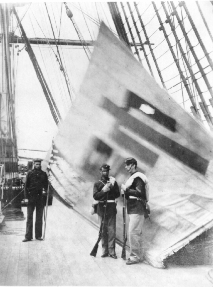 Charles Brown and two other servicemen standing in front of a captured Korean flag