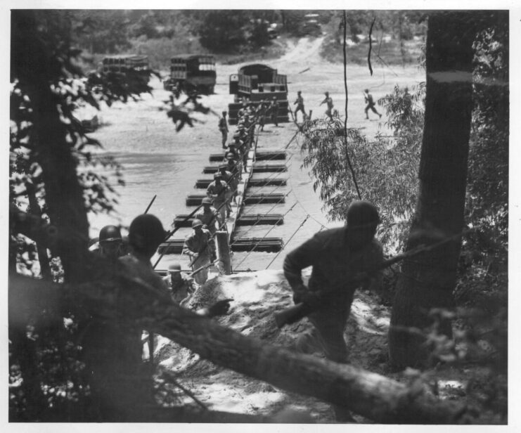 Members of the 442nd Regimental Combat Team running across a pontoon bridge