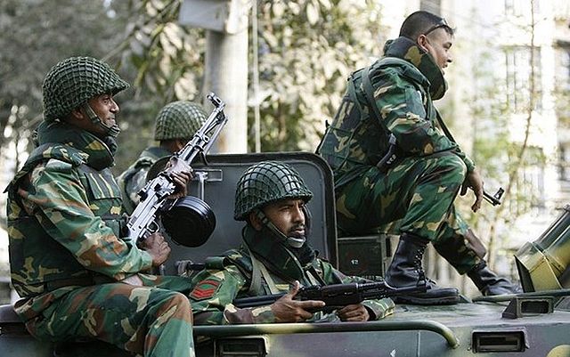 Four Bangladeshi soldiers sitting atop an armored vehicle