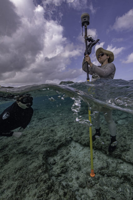 Diver swimming near a woman with a GPS device