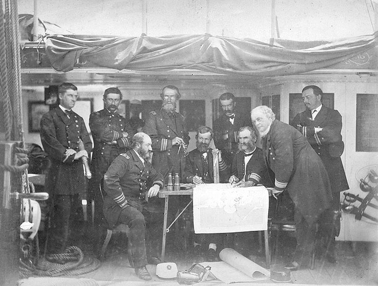 US Navy officers standing around a small wooden table