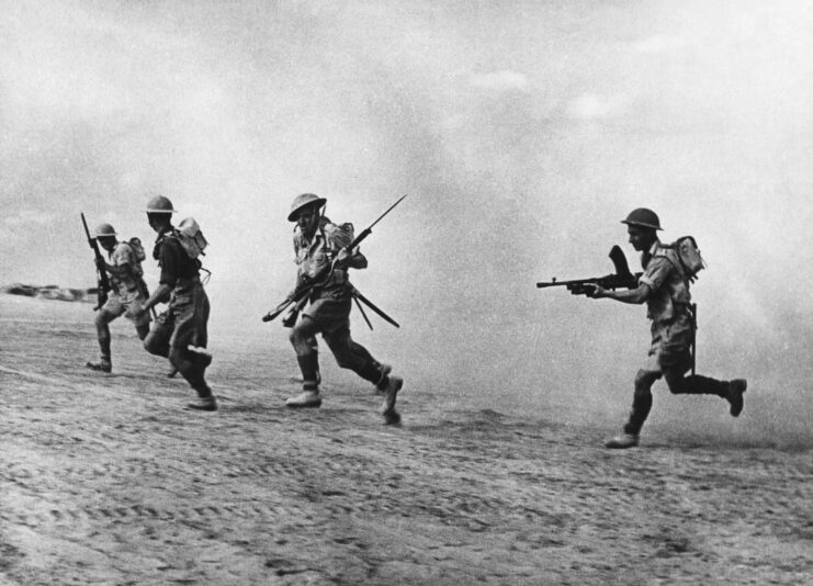 Four British infantrymen running through the desert