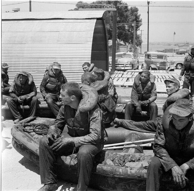 Members of an Underwater Demolition Team (UDT) sitting on an inflatable boat in their gear