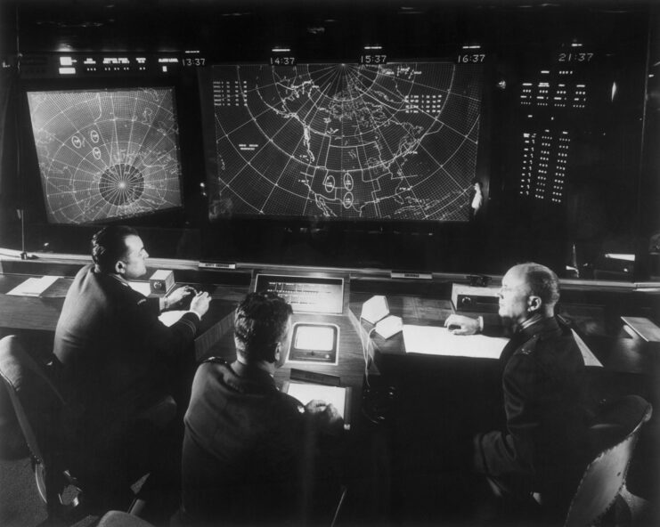 Three men sitting before NORAD's computer system