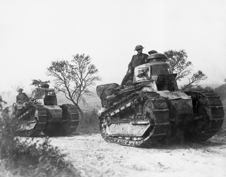 US troops driving tanks along a dirt road