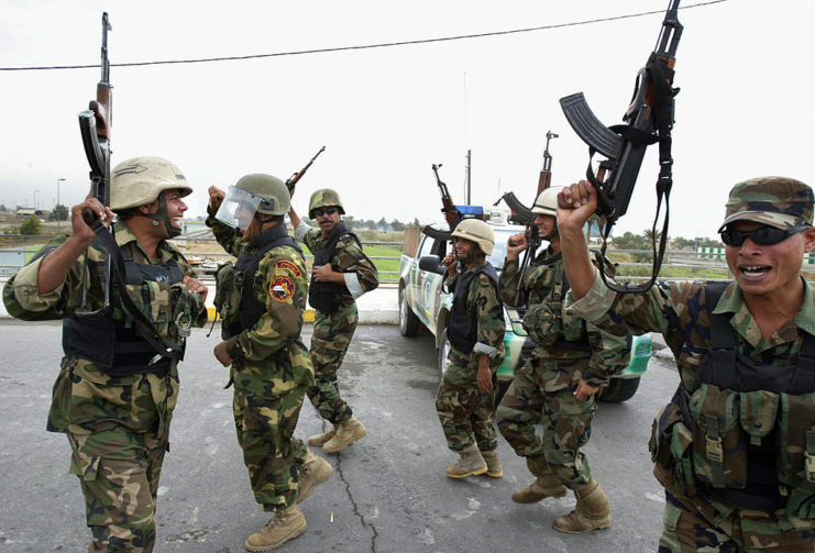 Iraqi soldiers dancing in the middle of a street with their weapons held high