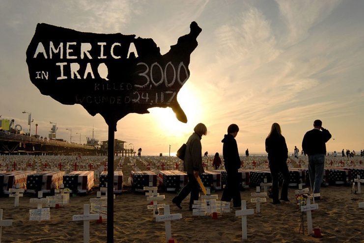 Four individuals standing before crosses in the sand