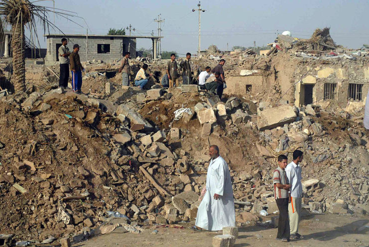 Iraqi men standing among the rubble of destroyed buildings