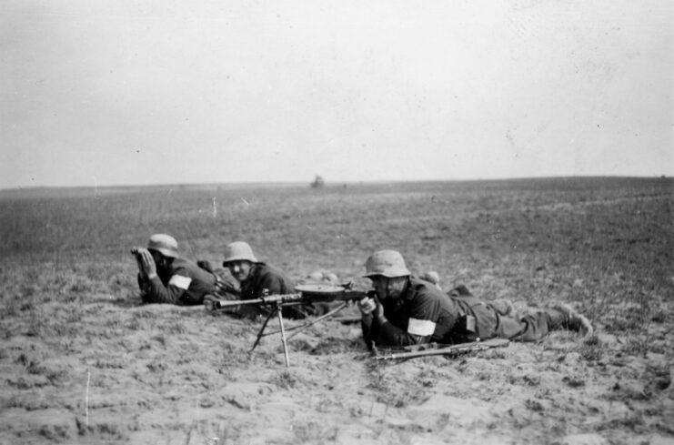 One soldier aiming a Degtyaryov DP-27 light machine gun while two others lie beside him