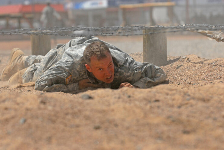 US soldier crawling beneath barbed wire