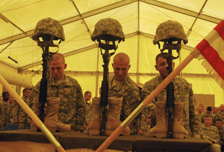 Three soldiers standing before three Battlefield Crosses erected inside a tent