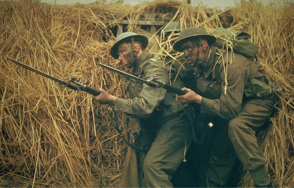 Two British Commandos ducking in tall grass with their weapons