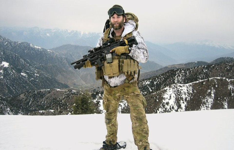 Jason Everman standing atop a snowy ridge while holding a weapon