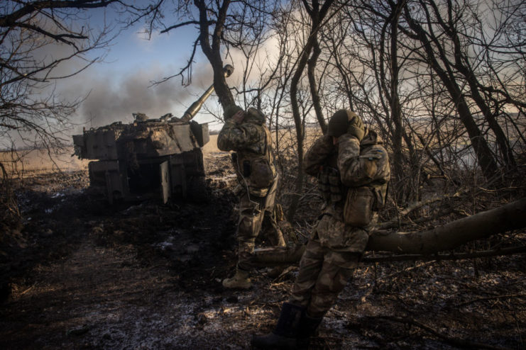 Ukrainian artillerymen firing an M109 howitzer from a wooded area