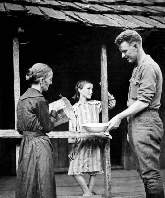 Sgt Alvin York standing on a house deck with his mother and younger sister