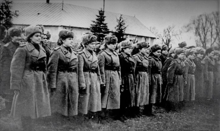 Night Witches standing at attention in front of a building