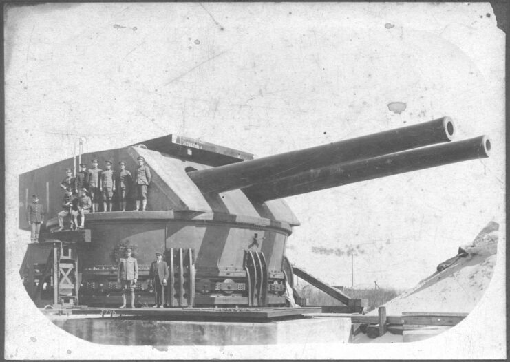 US military personnel standing with Fort Drum's 14-inch gun turret