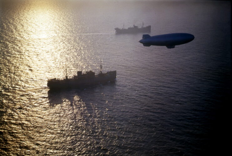 Blimp hovering over two merchant ships at sea