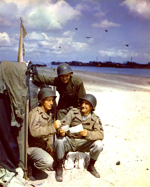 R.A Forbis, John Krisa and V.E. Holtz reading letters on a beach